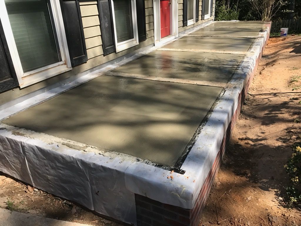 A concrete porch is being built in front of a house.