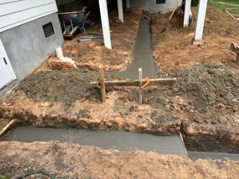 A concrete walkway is being built in front of a house.