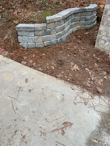 A brick wall is sitting next to a concrete sidewalk.
