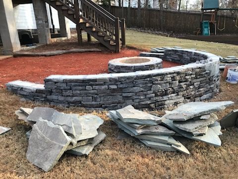 A fire pit is being built in a backyard next to a pile of rocks.