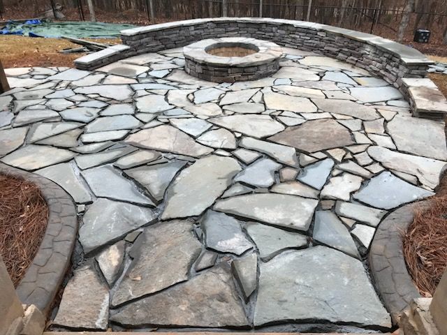 A stone patio with a fire pit in the middle.