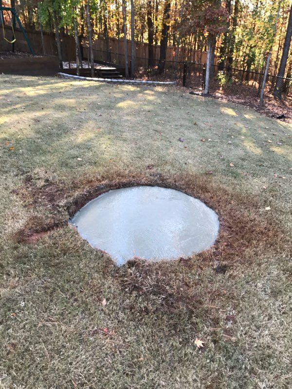A concrete circle in the middle of a lush green field.