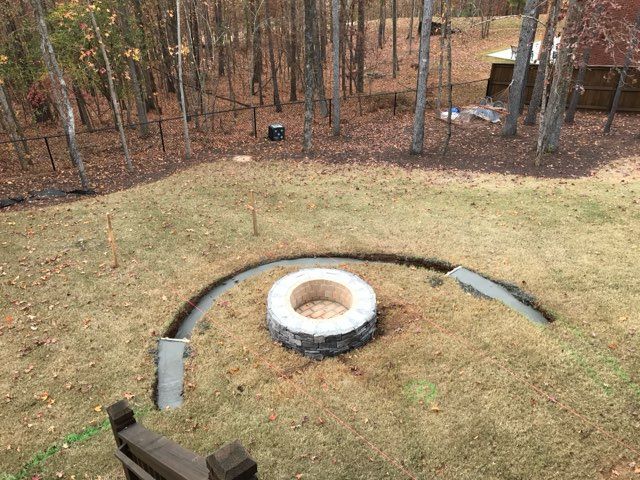 A fire pit is sitting in the middle of a lush green field.