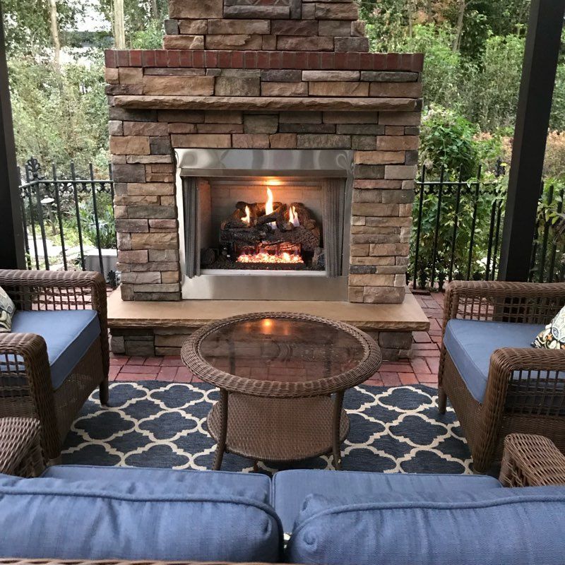 A patio with a fireplace and wicker furniture