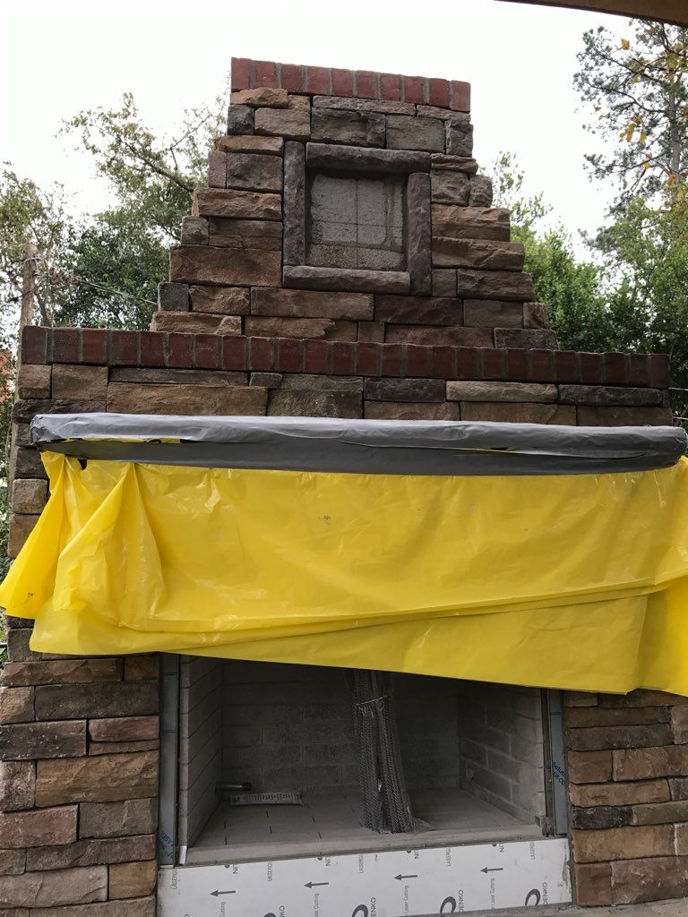 A brick fireplace with a yellow tarp covering it