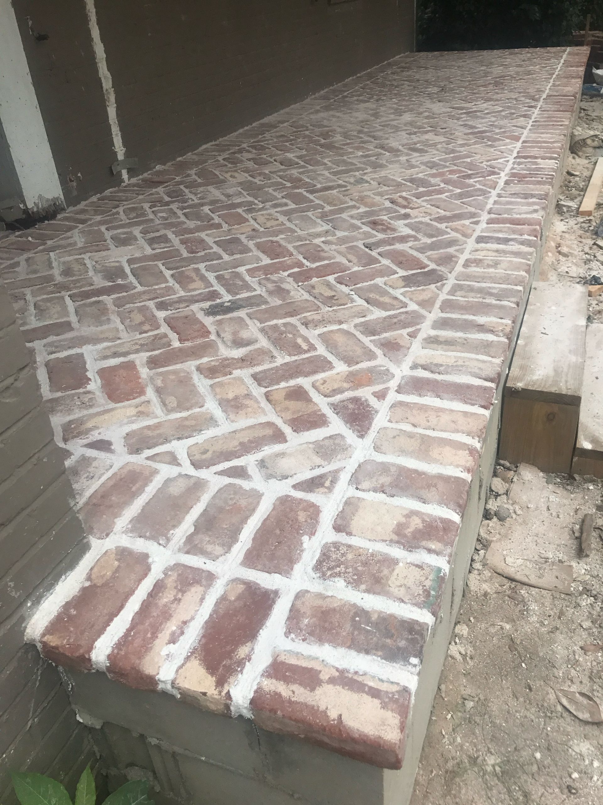 A brick walkway is being built on the side of a house.