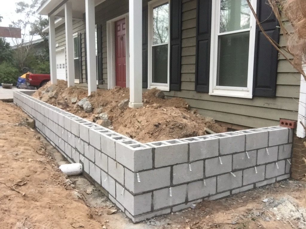 A brick wall is being built in front of a house