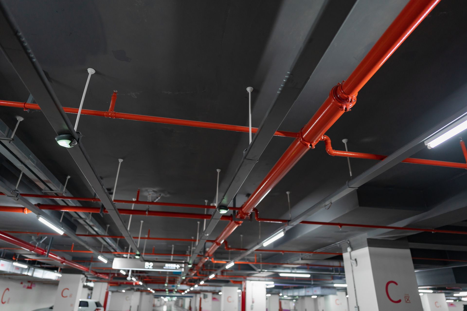 Un soffitto di un parcheggio con tubi rossi appesi