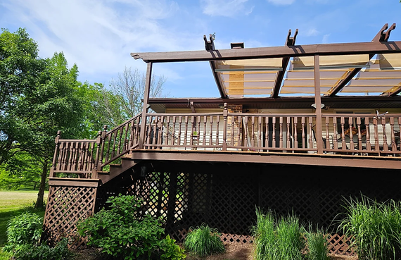 A large wooden deck with a pergola on top of it