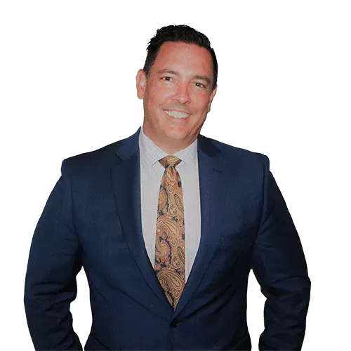 A man in a suit and tie is standing in front of a white wall.