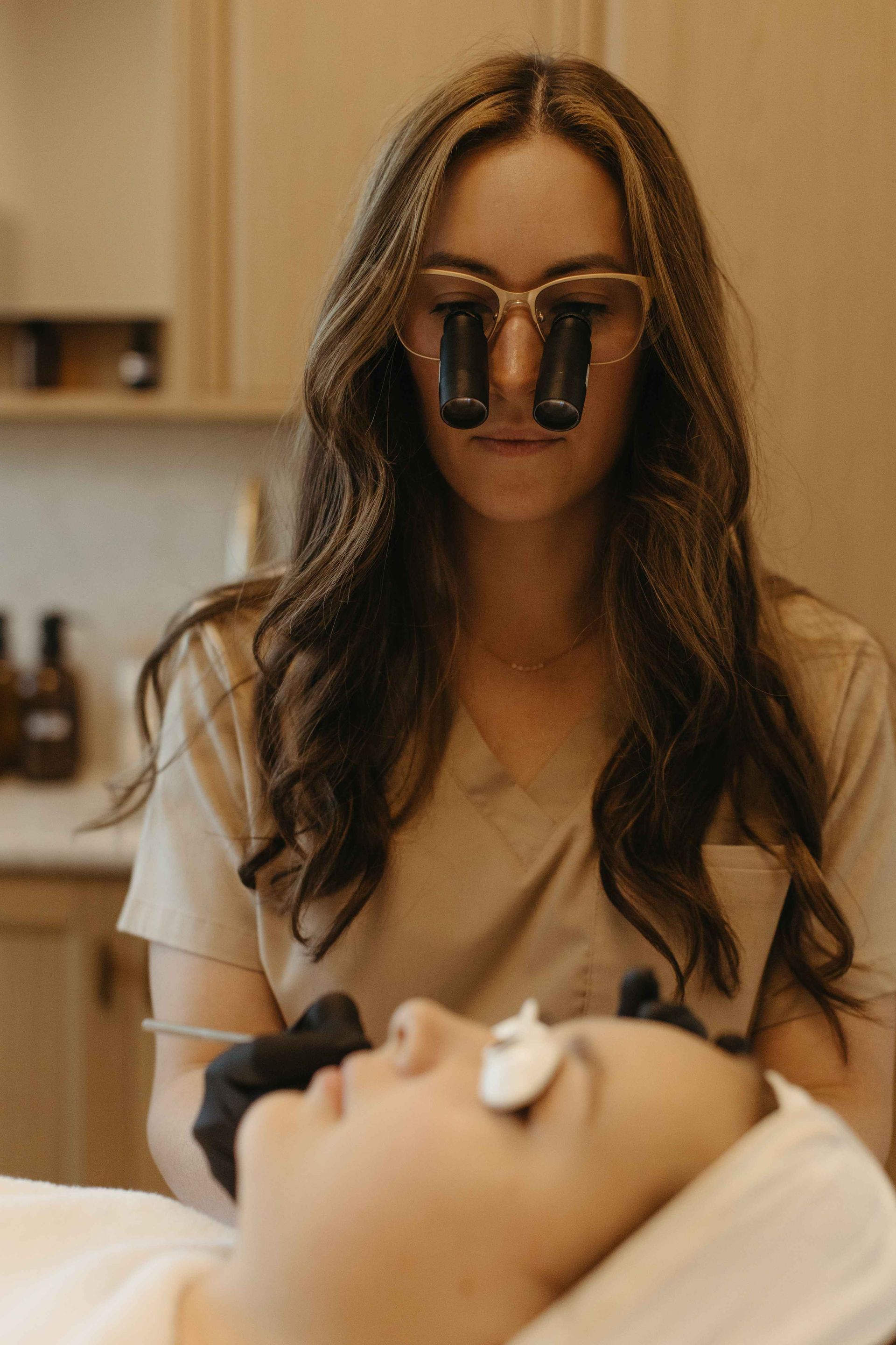 Woman with magnifying glasses examining a patient in a medical office.