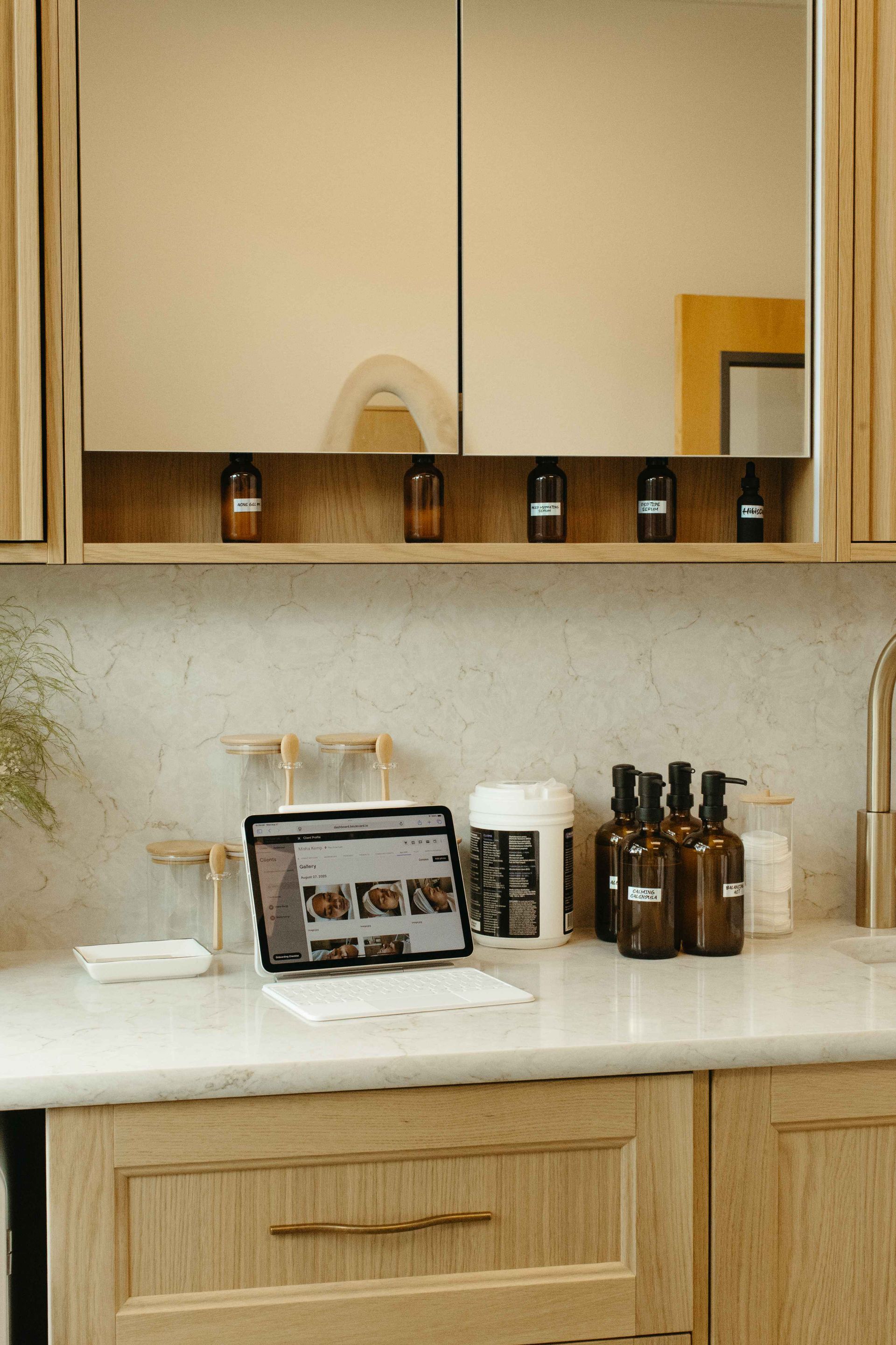 Countertop with open laptop, brown bottles, and wooden cabinets.