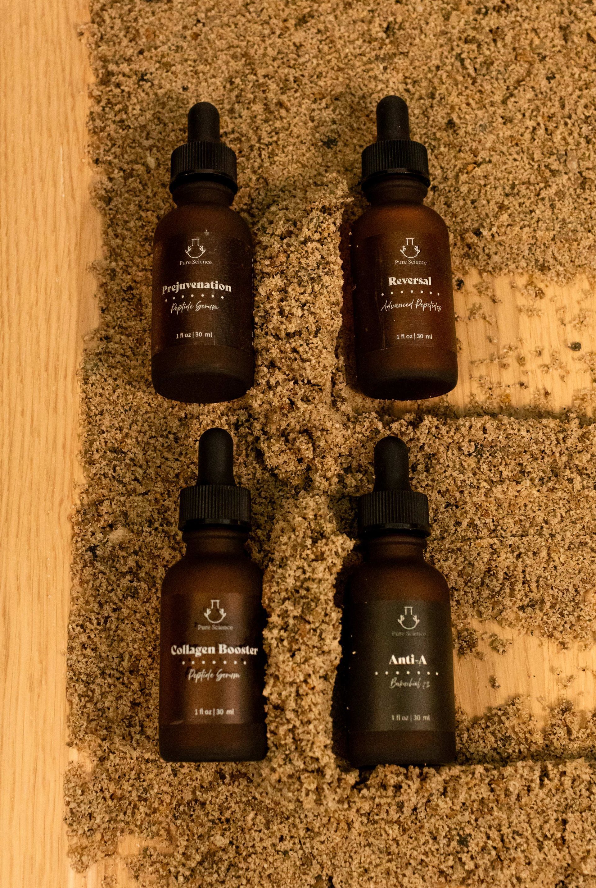 Four brown dropper bottles on a textured surface, each with a label.