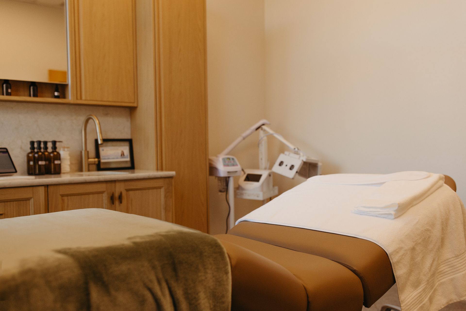 Spa room with two massage tables, neutral colors, bright lighting.