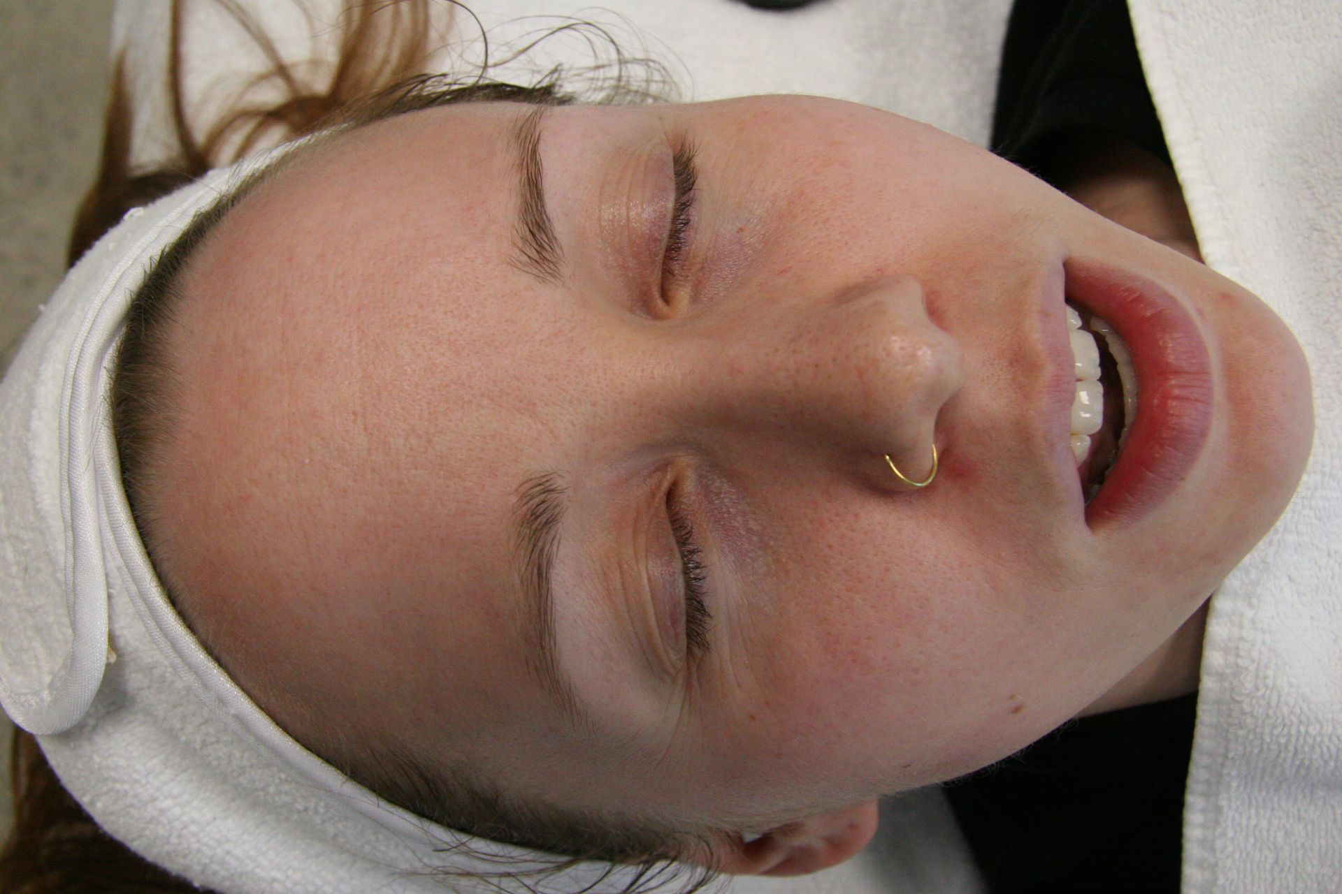 A woman is laying down with her eyes closed and a headband on her head.