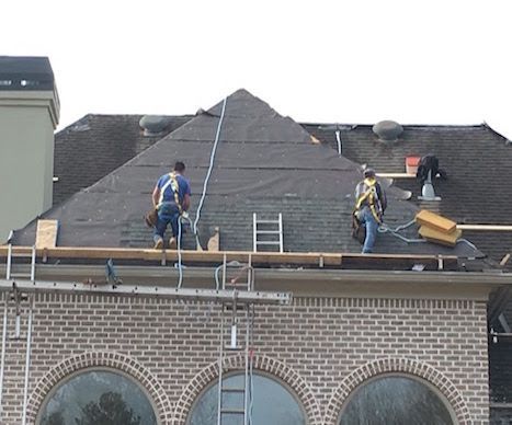 Two men are working on the roof of a brick building