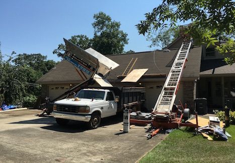 A white truck is parked in front of a house with a ladder attached to it.