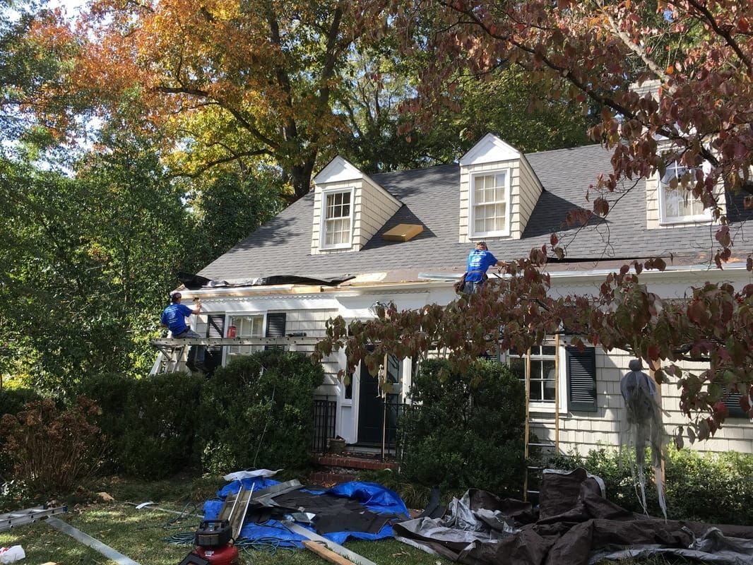 A group of people are working on the roof of a house.