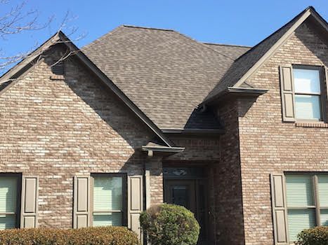 A large brick house with a gray roof and shutters.