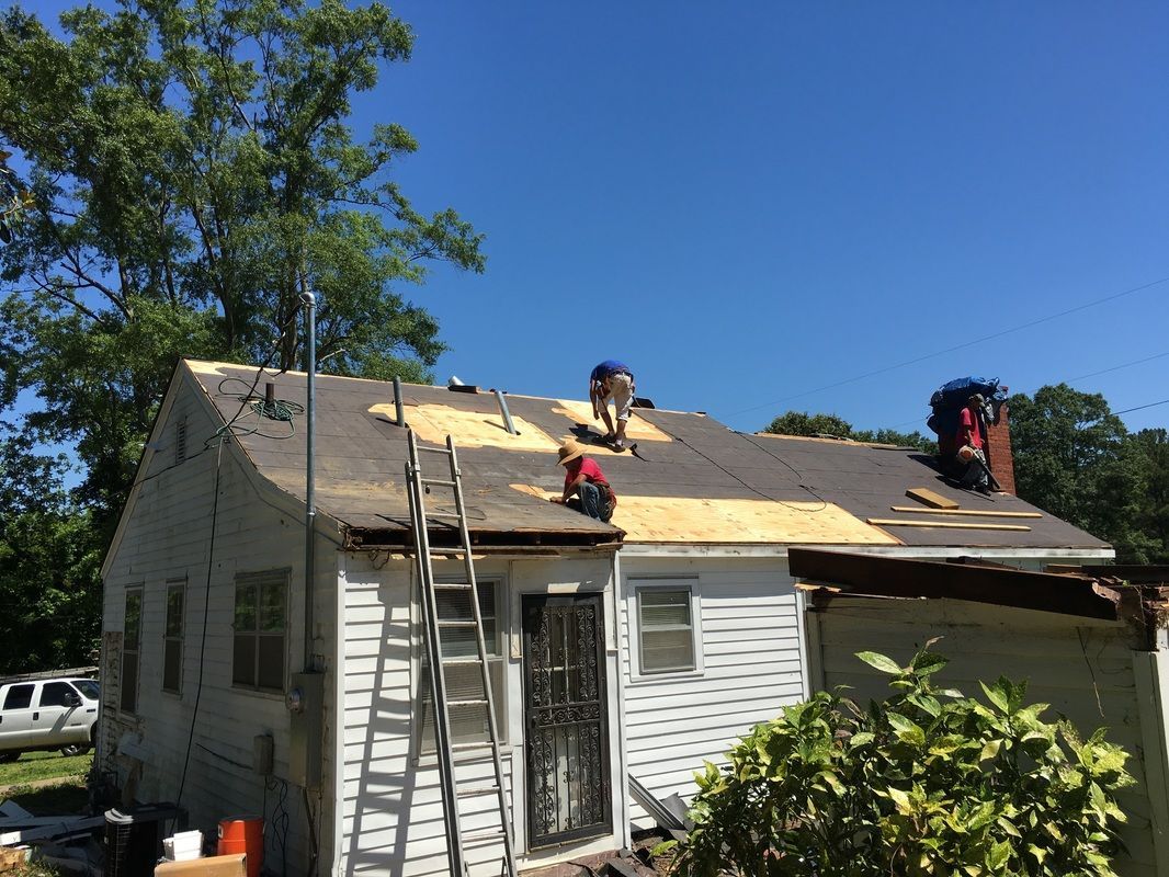 A group of people are working on the roof of a house.