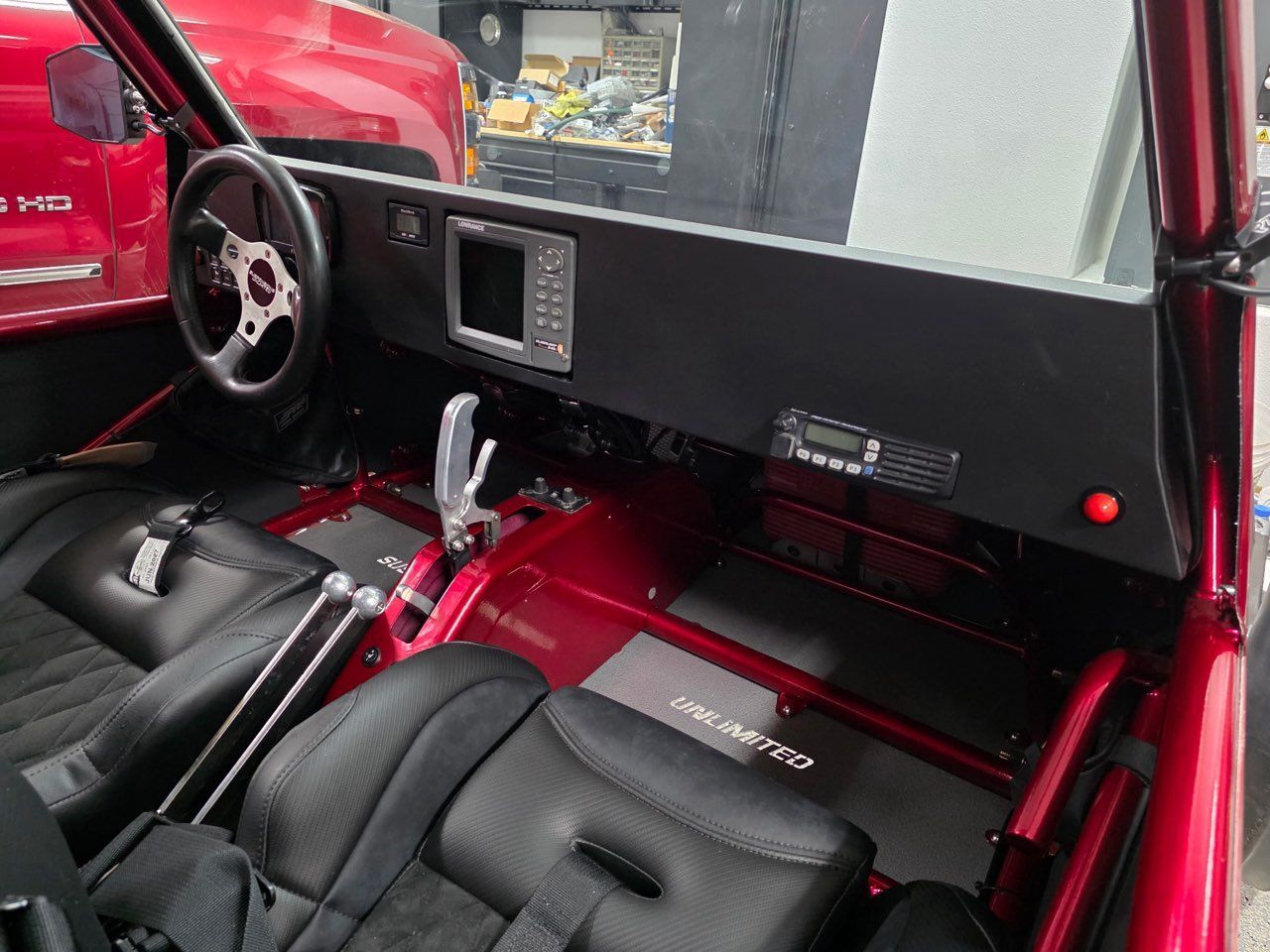Interior of a red buggy, showcasing the dashboard, black seats, steering wheel, and roll cage.