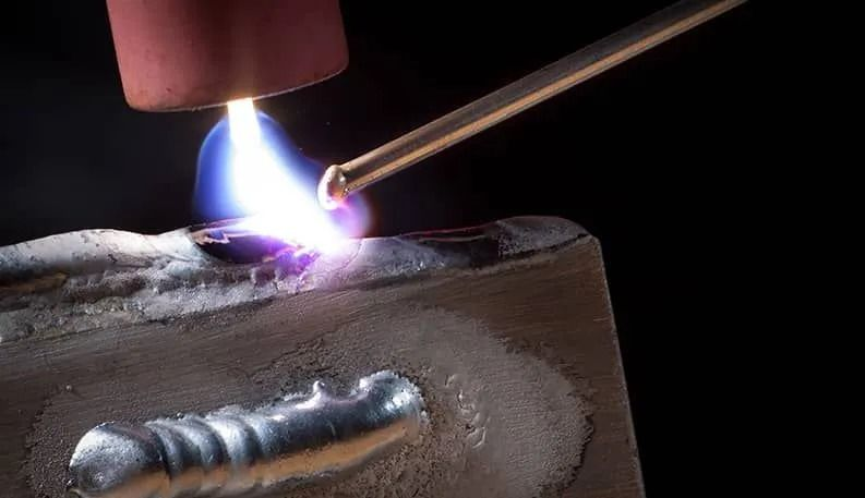 A person is welding a piece of metal with a torch.