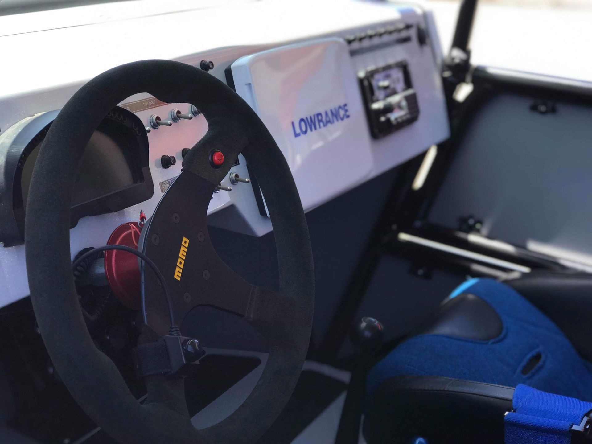 Off-road vehicle interior with black steering wheel, gauges, and a Lowrance display.