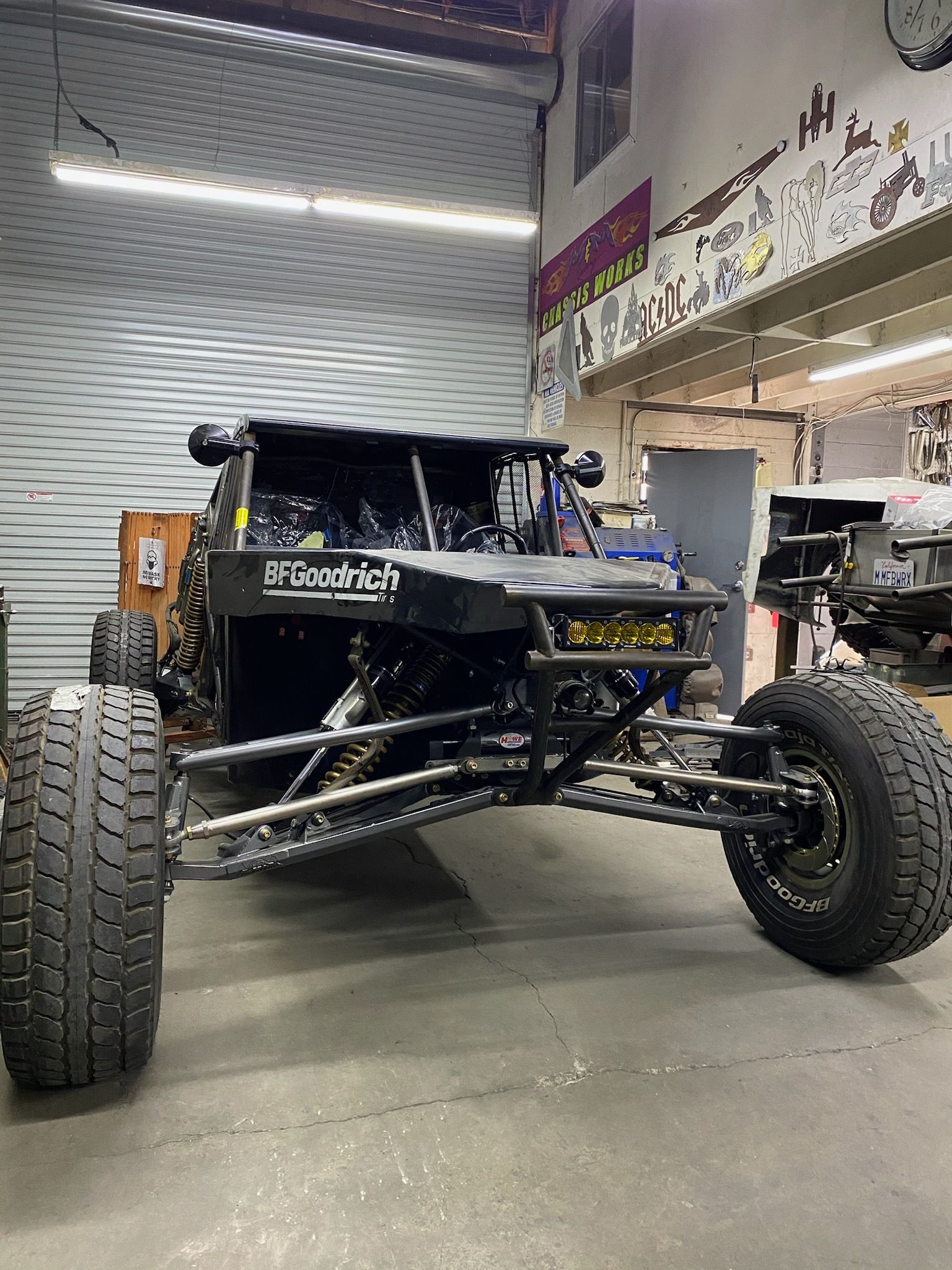 Black off-road vehicle with large tires in a garage setting.
