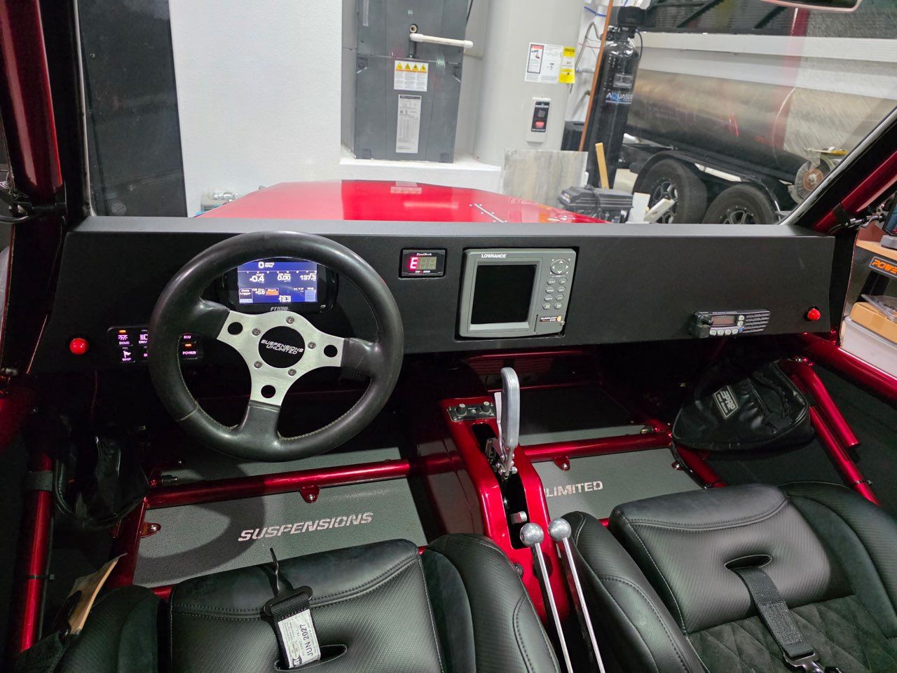 Red buggy interior with steering wheel, digital displays, and black leather seats.