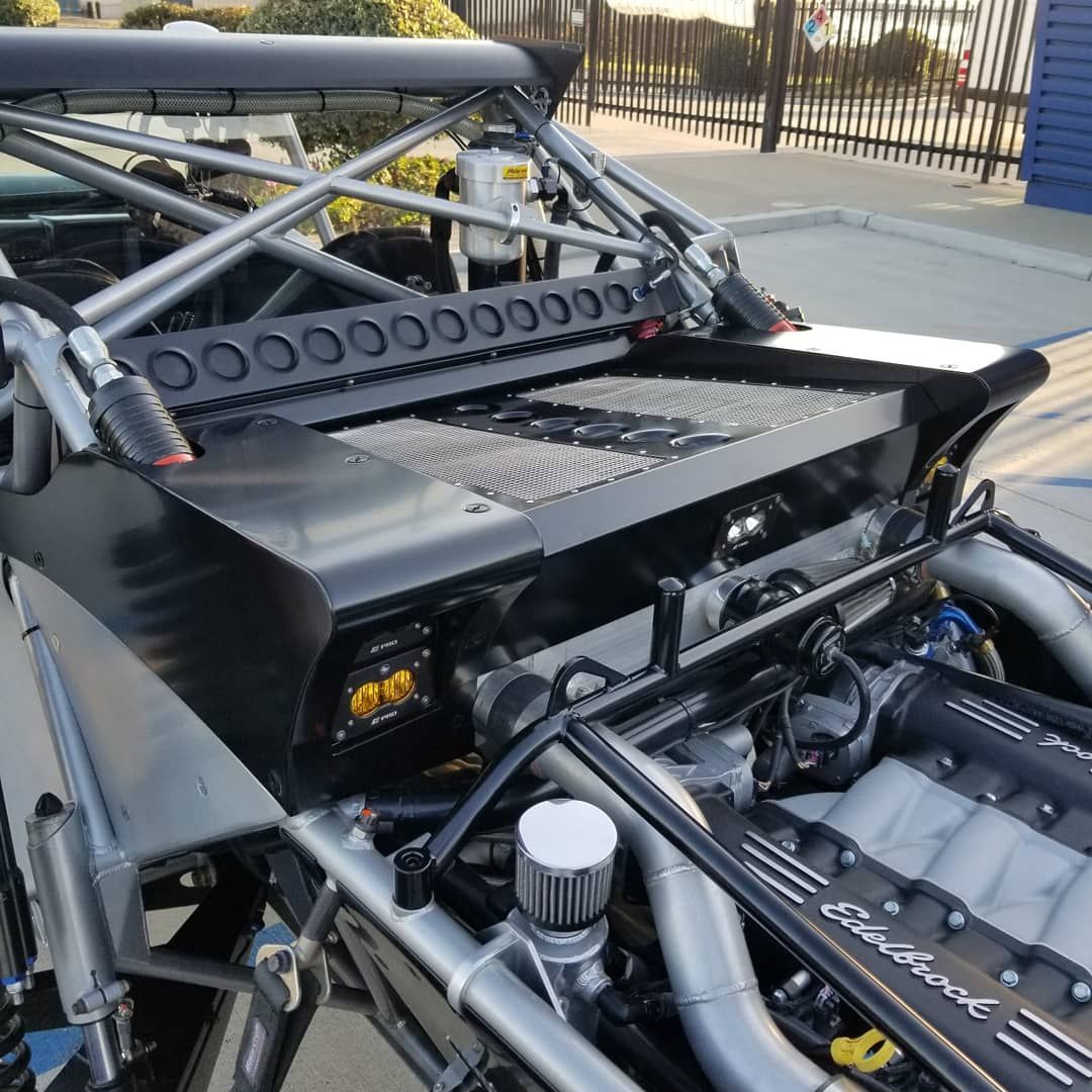 Off-road buggy with exposed engine, roll cage, black panels, and LED lights.