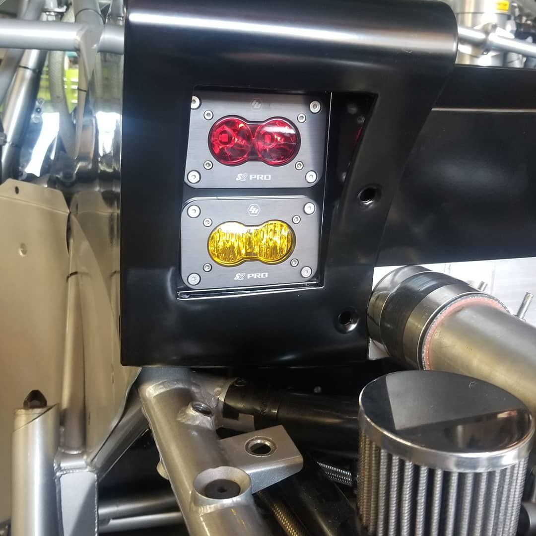 Red and yellow LED lights mounted on a black panel, part of a vehicle.