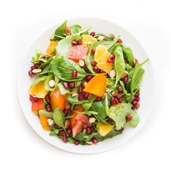 A white plate topped with a salad of fruit and vegetables.