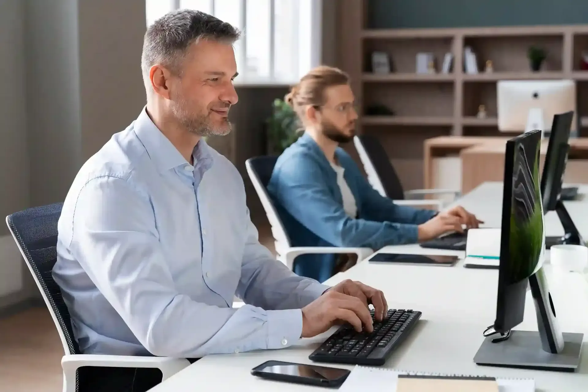 Two people using computers in an office while getting IT Support Services Long Island.