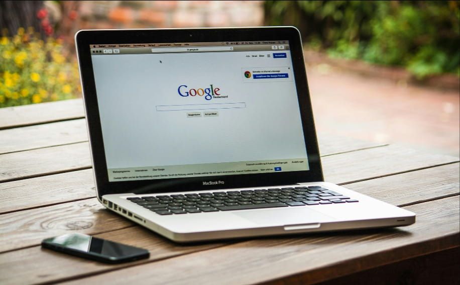 A laptop is open to a google page on a wooden table