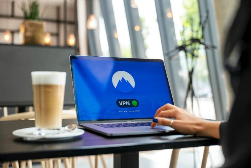A person is sitting at a table using a laptop computer.