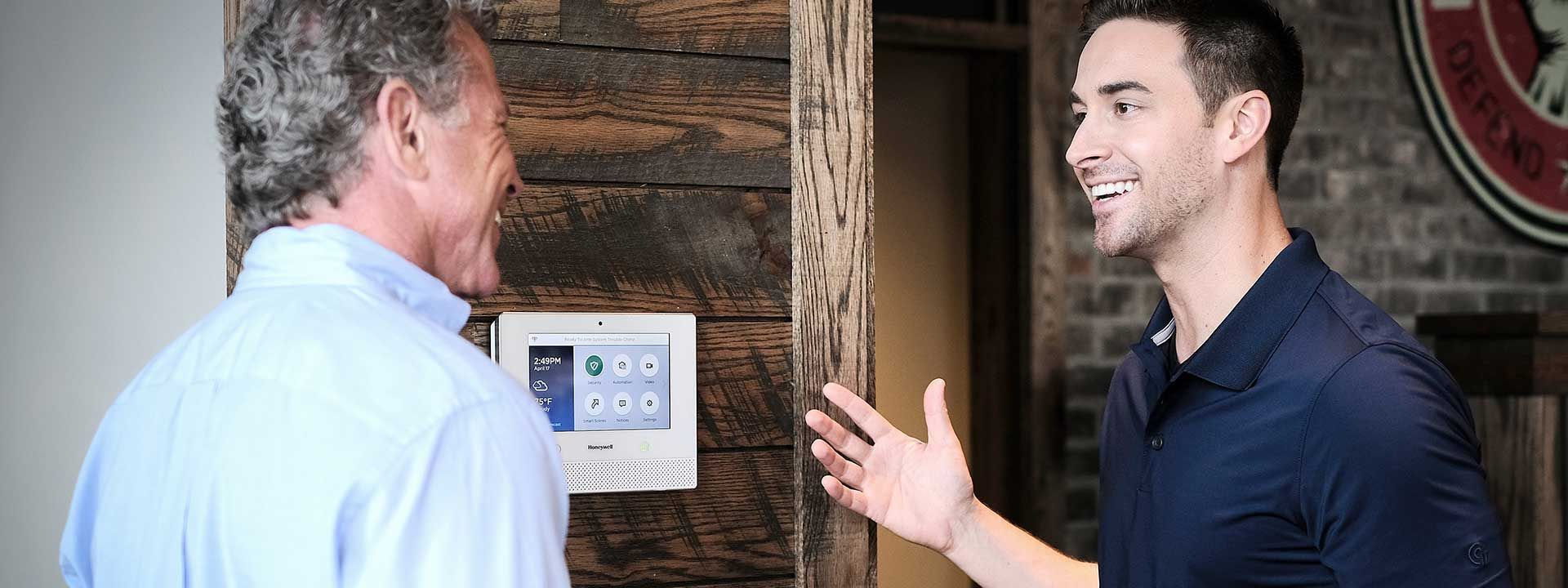 Two men are standing next to each other in a room talking to each other.