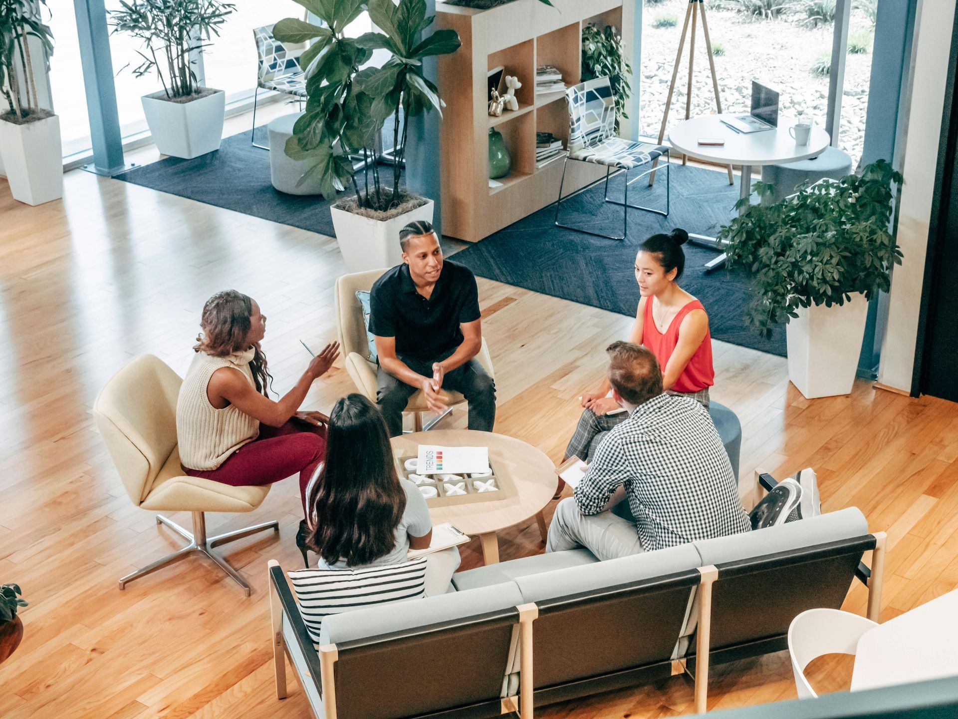 A group of people are sitting around a table in a living room.