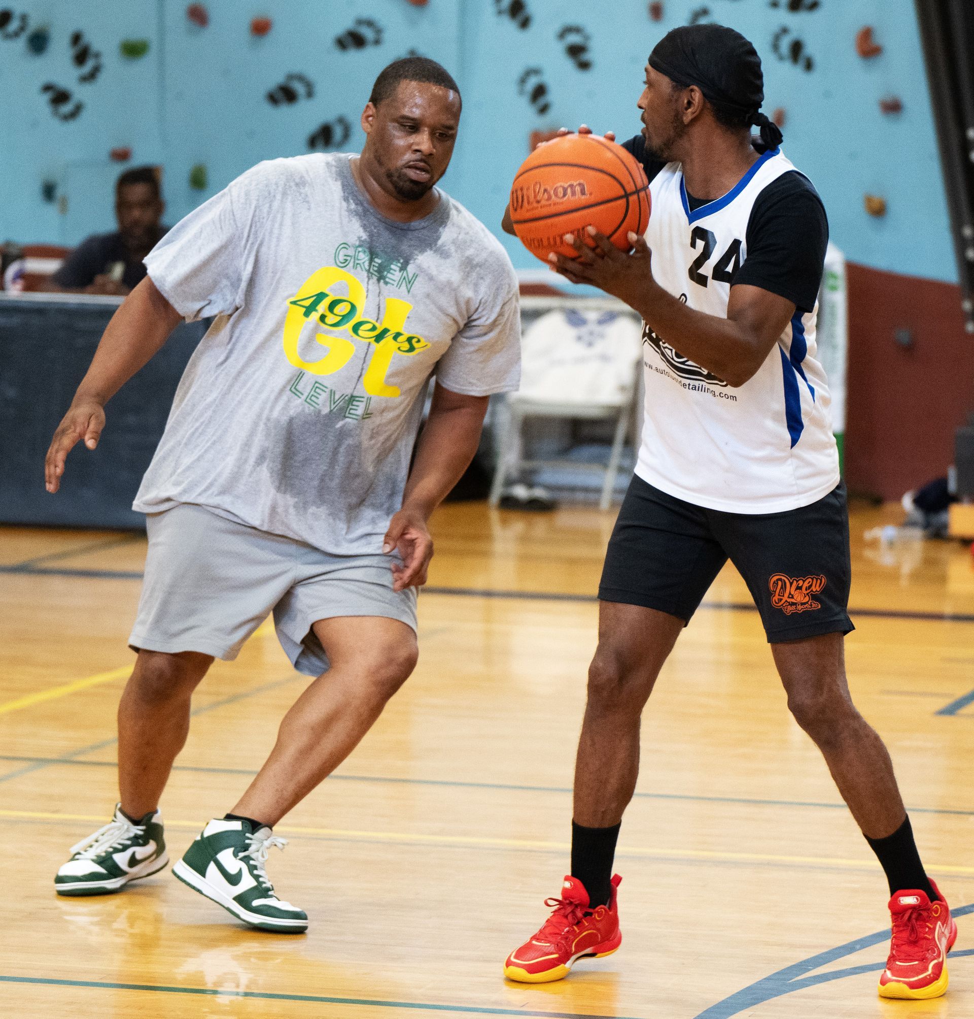 Two basketball players on an indoor court, one holding a ball while the other guards him.
