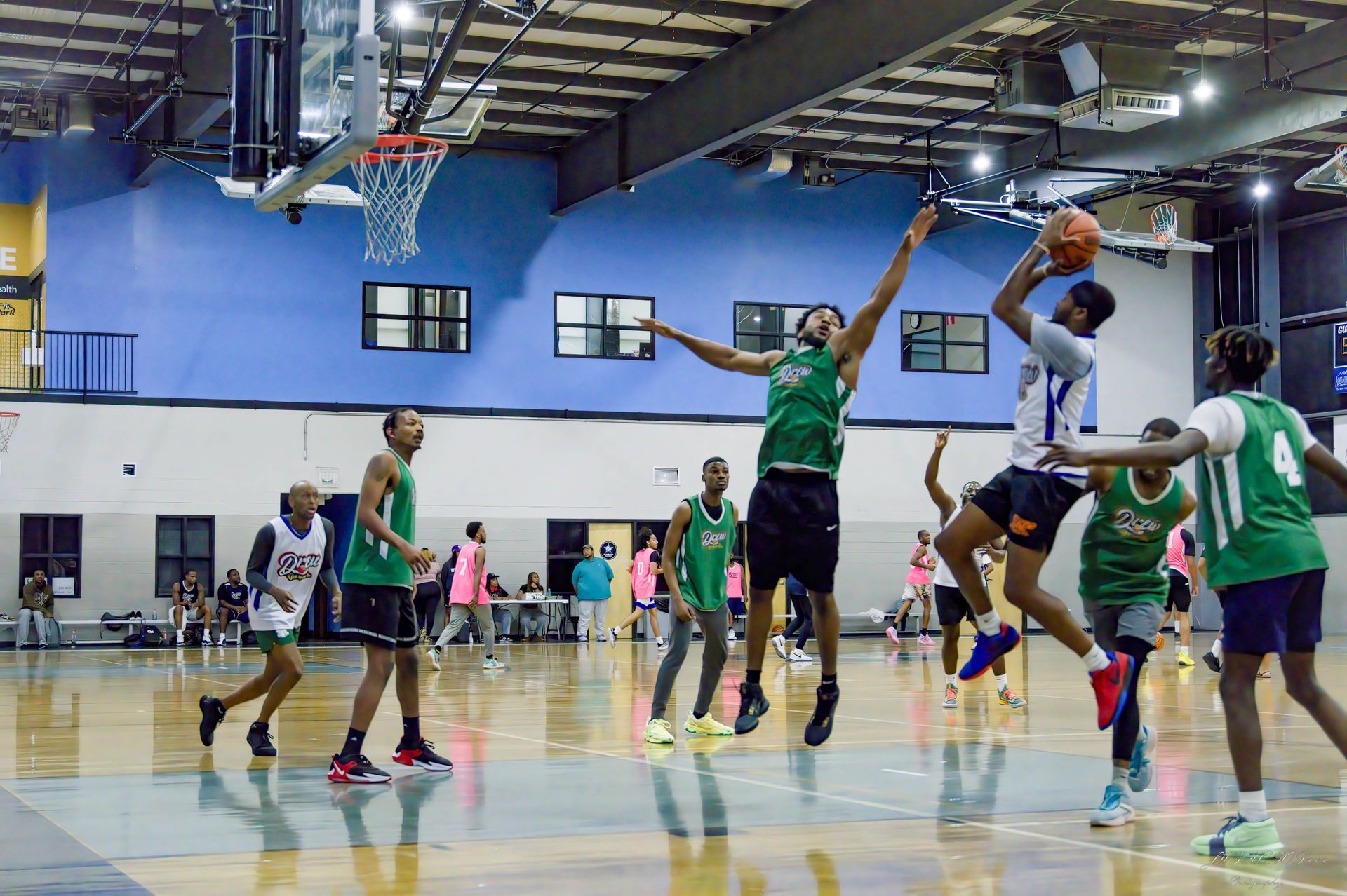 Players in green and white jerseys compete for a basketball during a game on an indoor court.