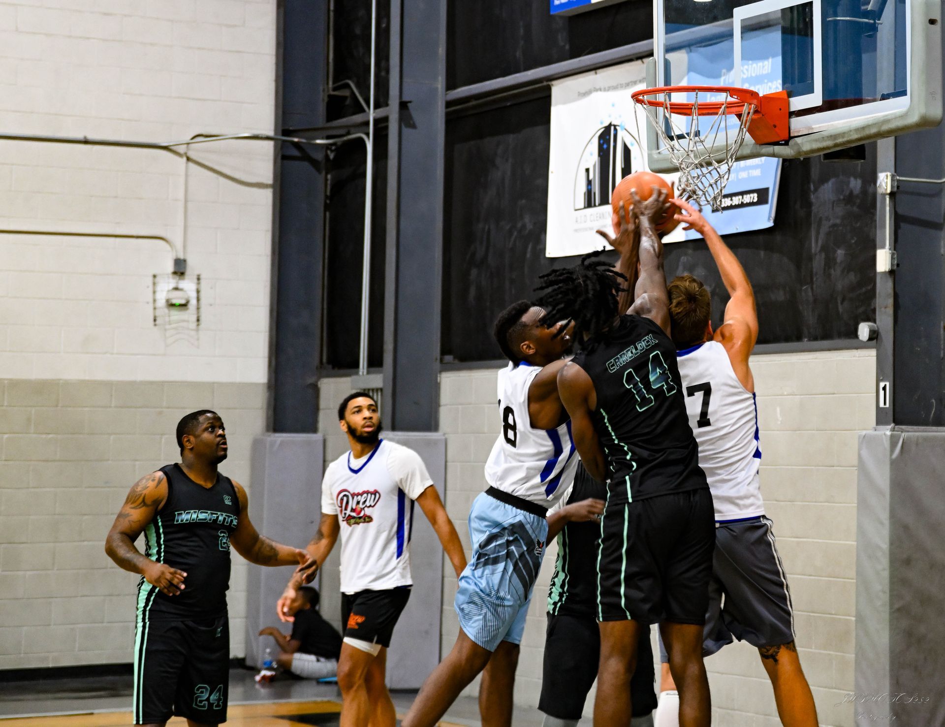 A group of basketball players competing for a rebound under the hoop during an indoor game.