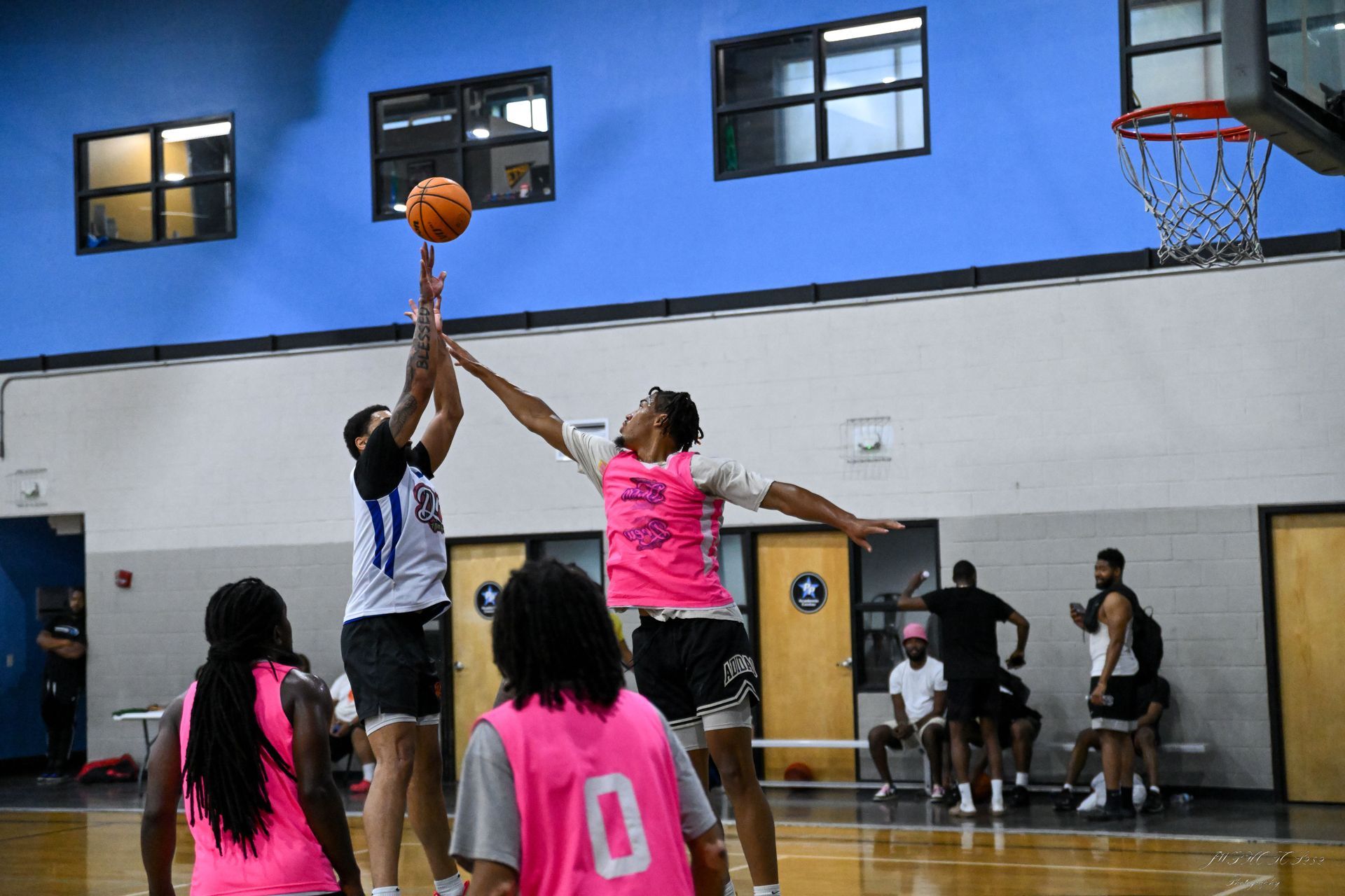 Two basketball players compete for a shot during a game on an indoor court.