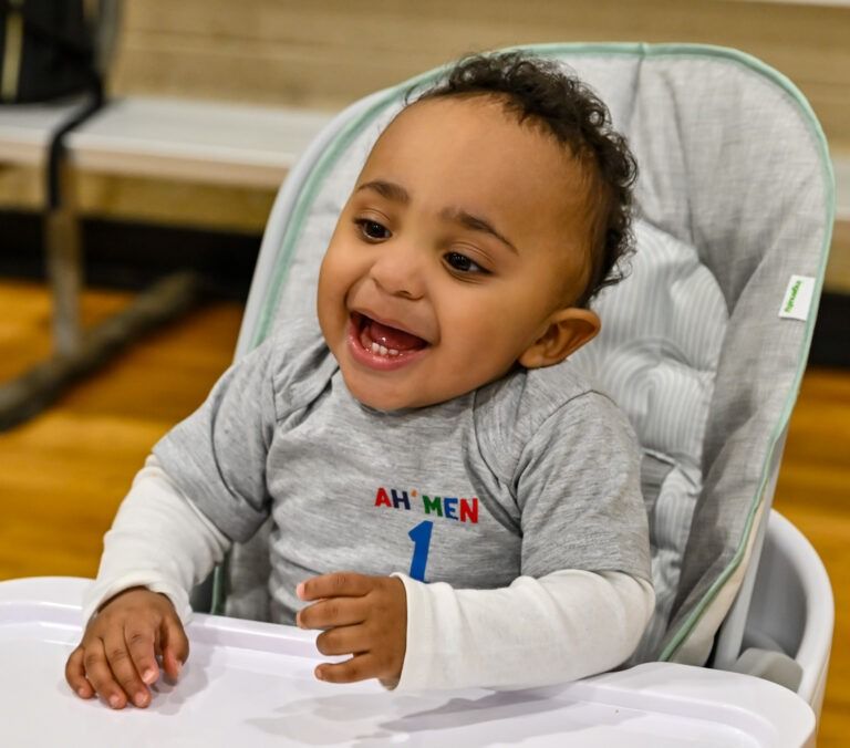 A happy toddler wearing a gray