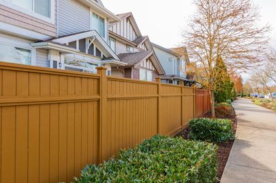 A wooden fence surrounds a row of houses in a residential area.