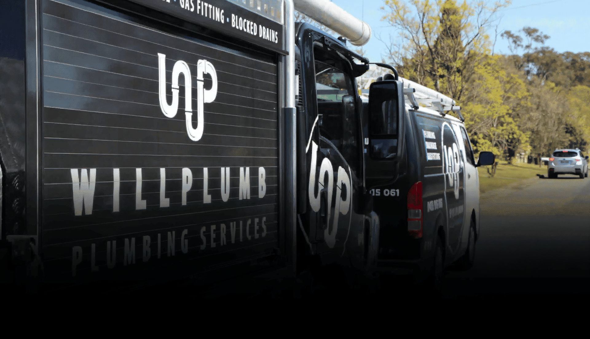 Black plumbing service vans parked on a road with the logo and text