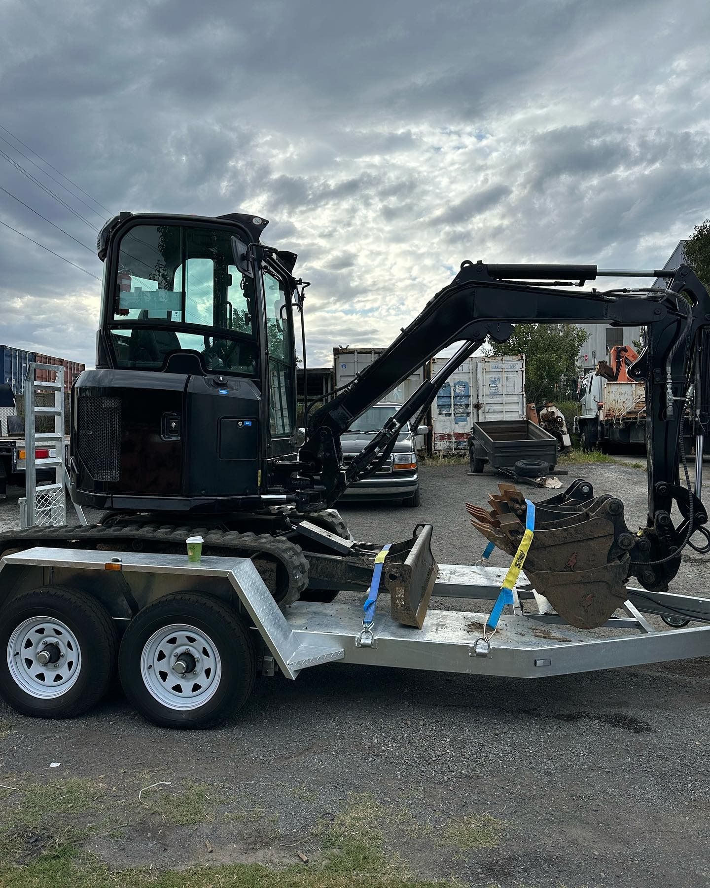 A black Willplumb work van with a roof rack parked in front of a white building with the Liebherr logo.