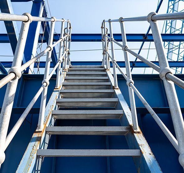 a man wearing a hard hat and safety vest is standing on a scaffolding.