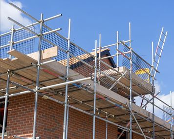 A brick building is being built with scaffolding and a ladder.