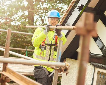 a construction worker is standing on a scaffolding on top of a building.