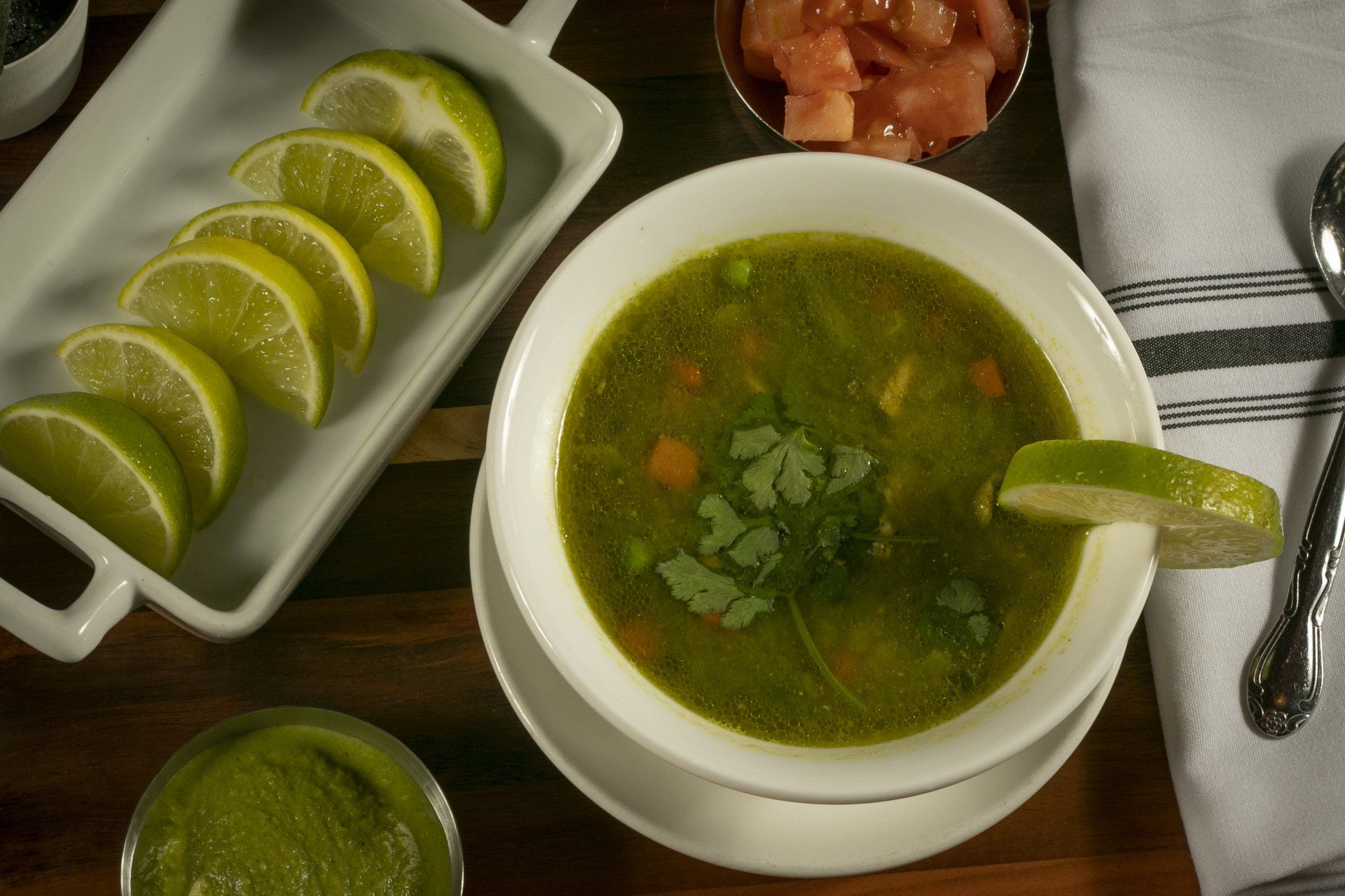 Soup with lime slices, salsa, and cilantro.