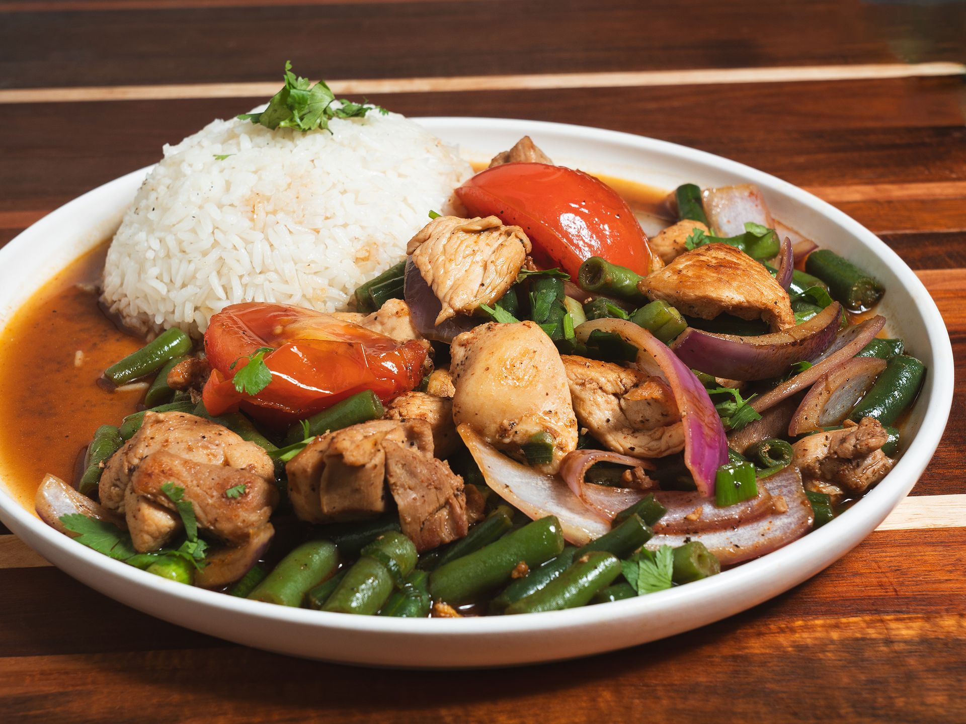 Chicken and vegetables served with rice on a white plate.